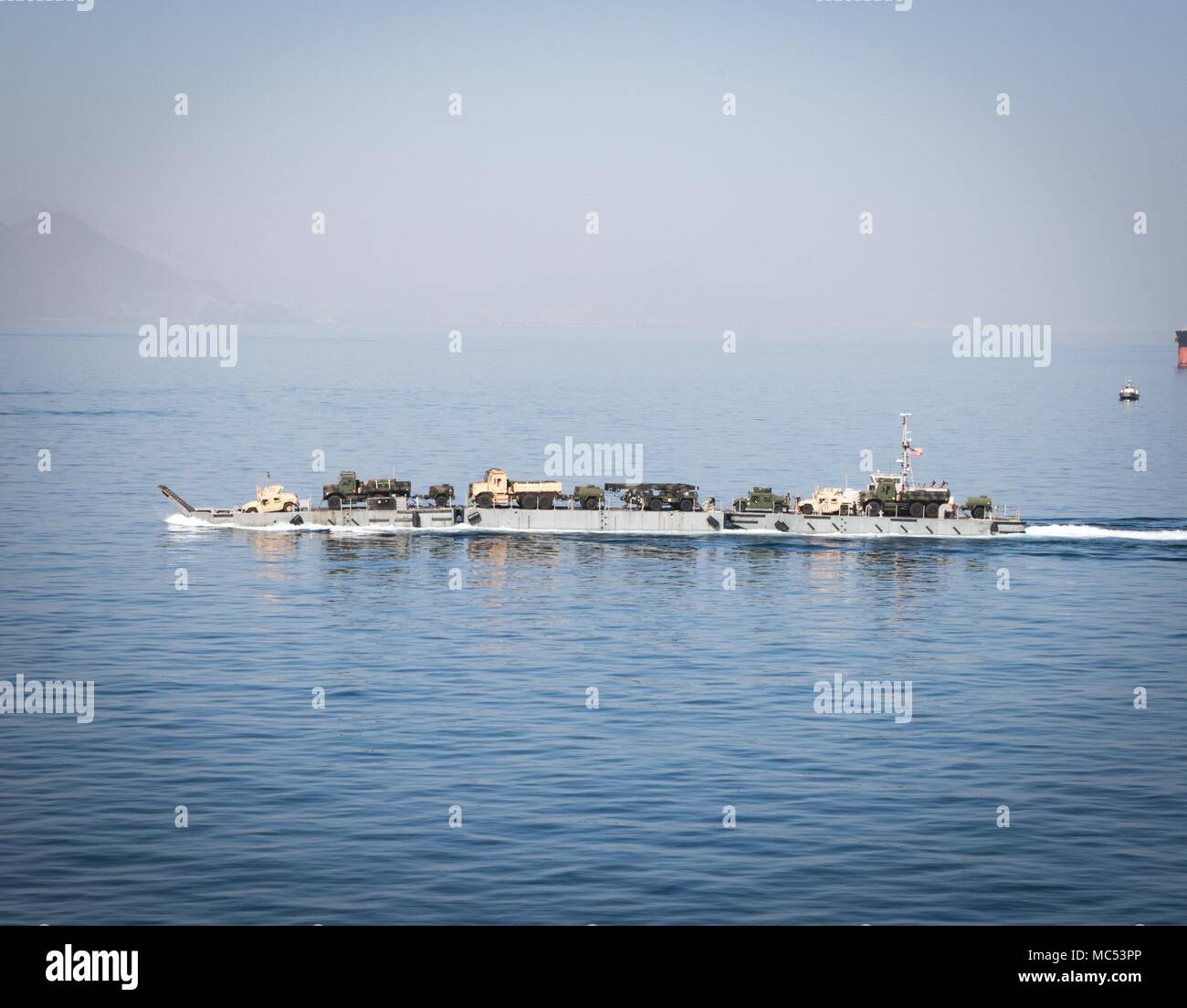 180123-N-KK081-275 U.S. 5ÈME ZONE DES OPÉRATIONS DE LA FLOTTE (janv. 23, 2018) de l'équipement militaire est transporté à l'aide d'un pont-jetée flottante décaissés à partir de l'USNS Seay (T-AKR 302) pour permettre le mouvement du navire à la terre de l'équipement sans l'utilisation d'un pilier dans le cadre de l'exercice Furie indigènes 18. L'exercice est conçu pour former les Marine-Air Terrain Force-Native Tâche Fury Marines et marins de la Marine américaine dans les opérations de la force et de prépositionnement maritime vise à accroître la compétence, étendre les niveaux de coopération, de renforcer les capacités maritimes, et à promouvoir la stabilité régionale à long terme et l'interopérabilité entre Banque D'Images