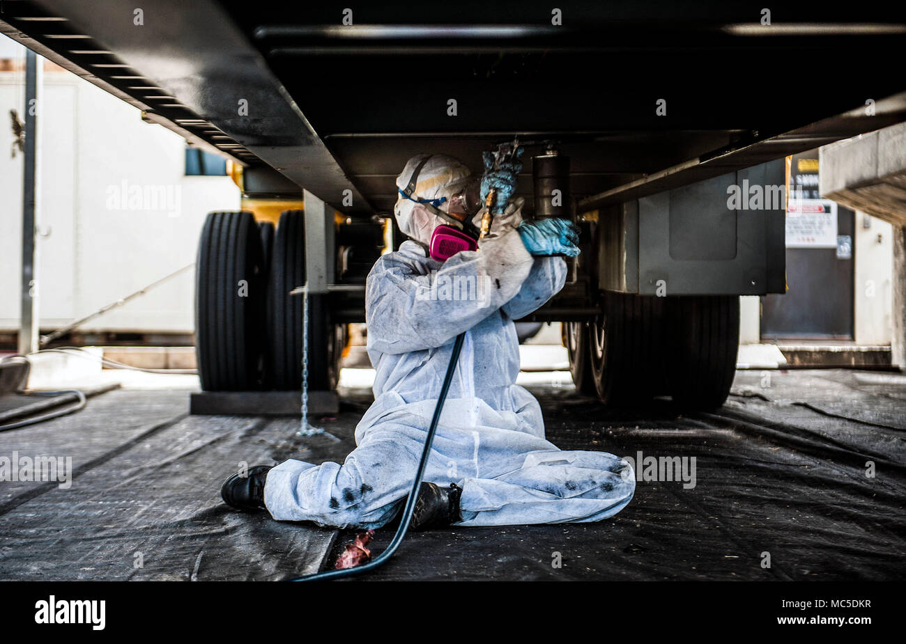 Masakazu Miyazato, 18e Escadron de préparation logistique technicien de réparation carrosserie, applique une sous-couche de protection sur une remorque, le 3 avril 2018, à Kadena Air Base, au Japon. Les véhicules mis à jour par 18e RL sont utilisés pour la sécurité, la construction, et les opérations quotidiennes. (U.S. Air Force photo par Naoto Anazawa) Banque D'Images