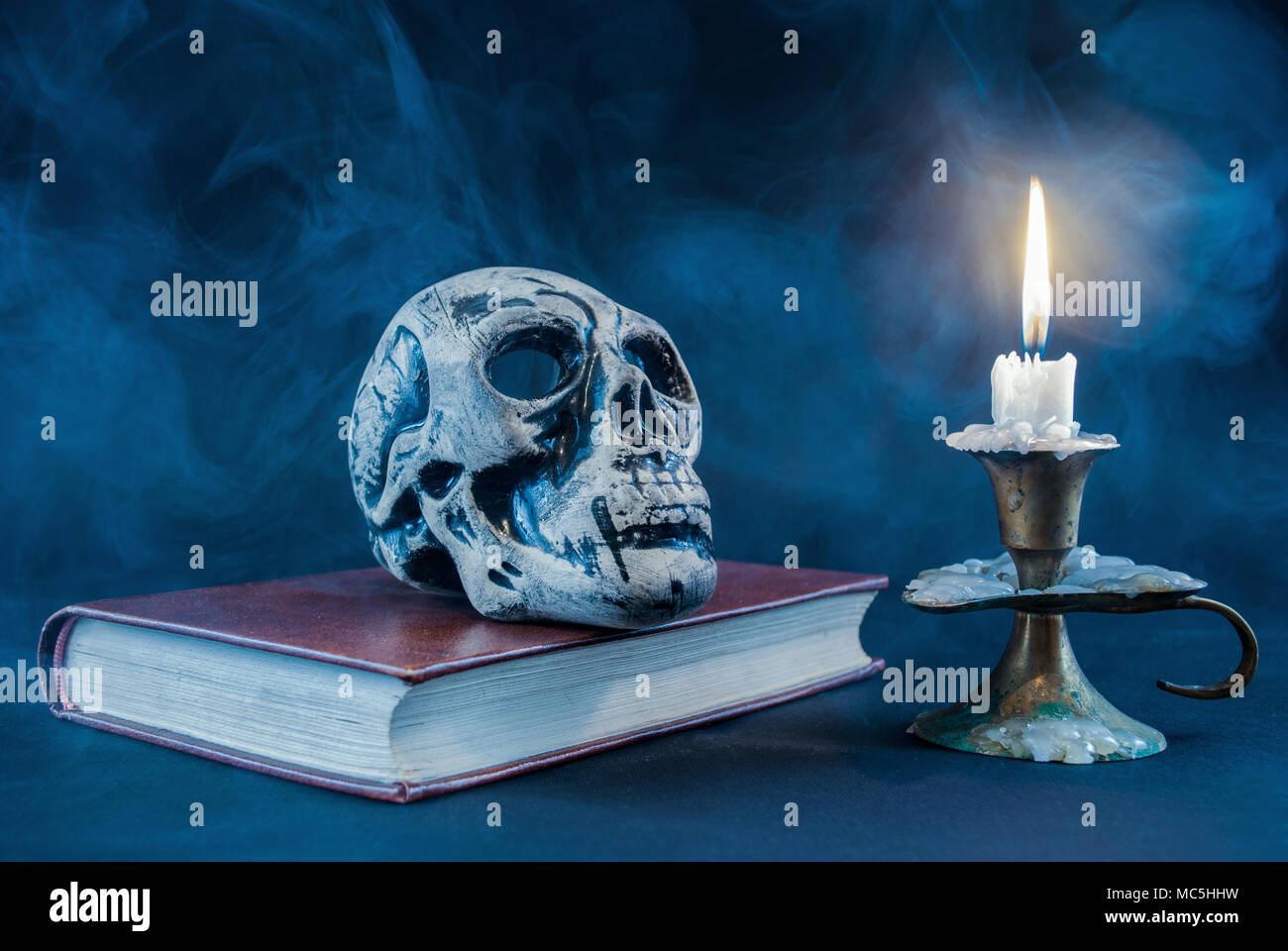Crâne gothique sur old book and candle en chandelier sur fond sombre et fumé. Halloween concept. Banque D'Images