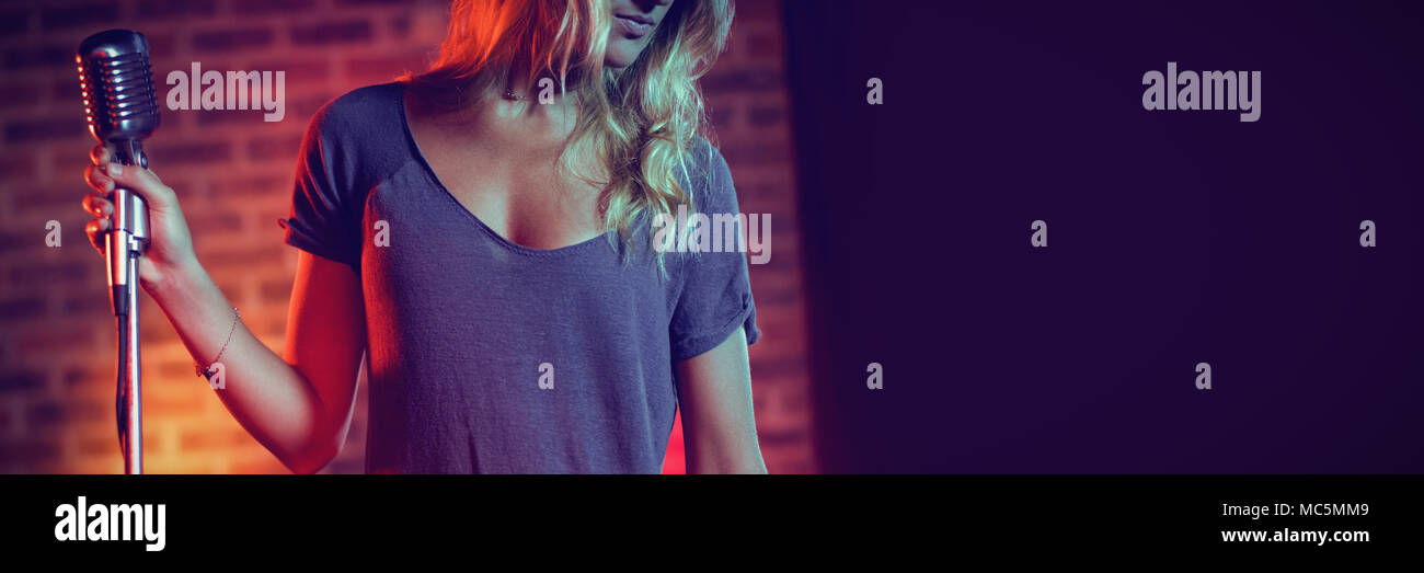 Chanteuse avec microphone standing in nightclub Banque D'Images