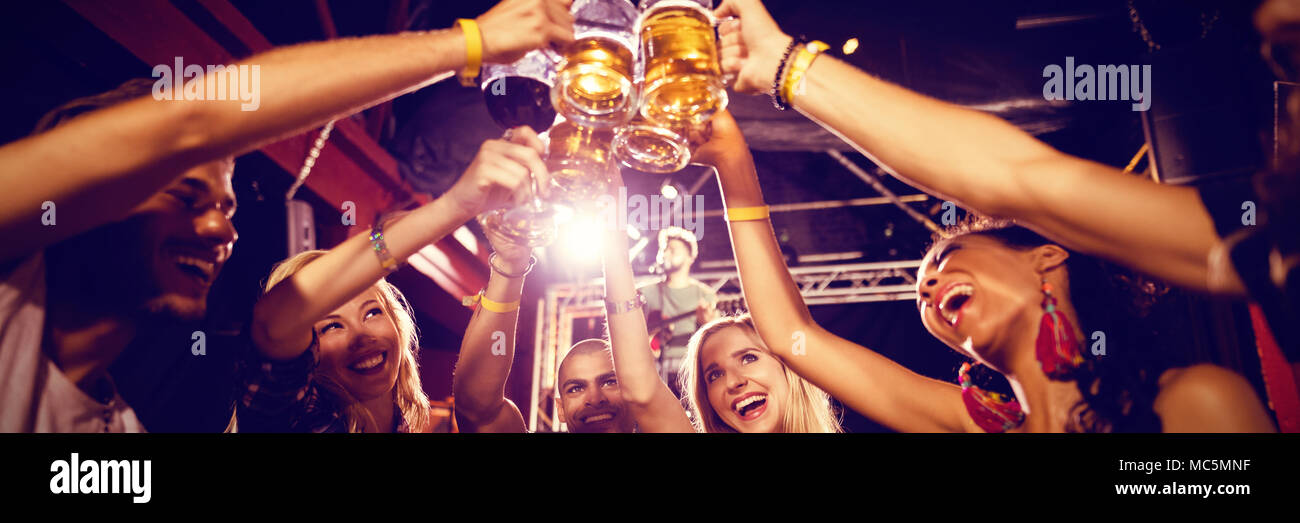 Friends toasting beer glasses at table in club Banque D'Images