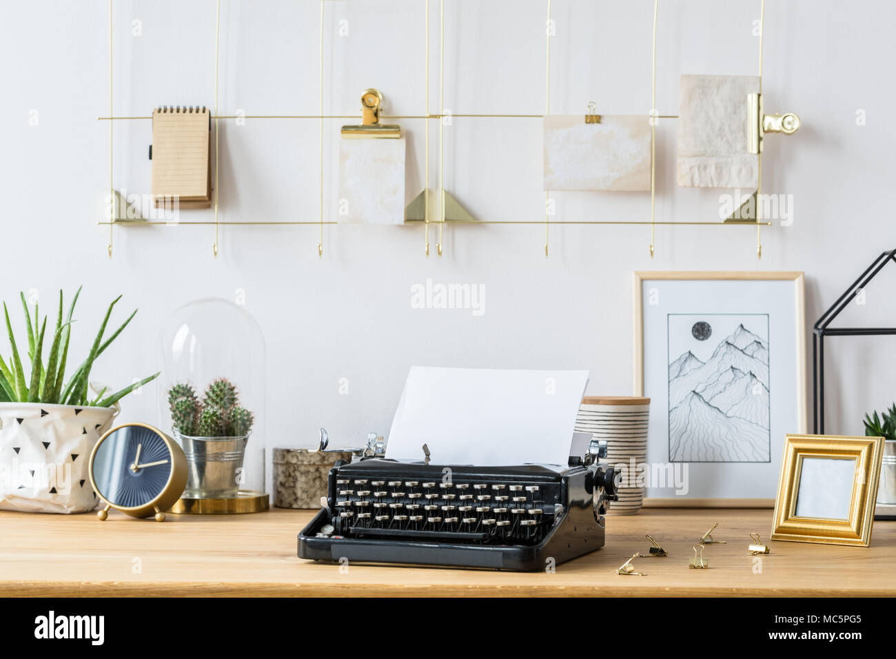 Un cadre doré organisateur sur un mur blanc au-dessus d'un bureau avec une machine à écrire vintage, noir, plantes grasses, cadres et décorations Banque D'Images