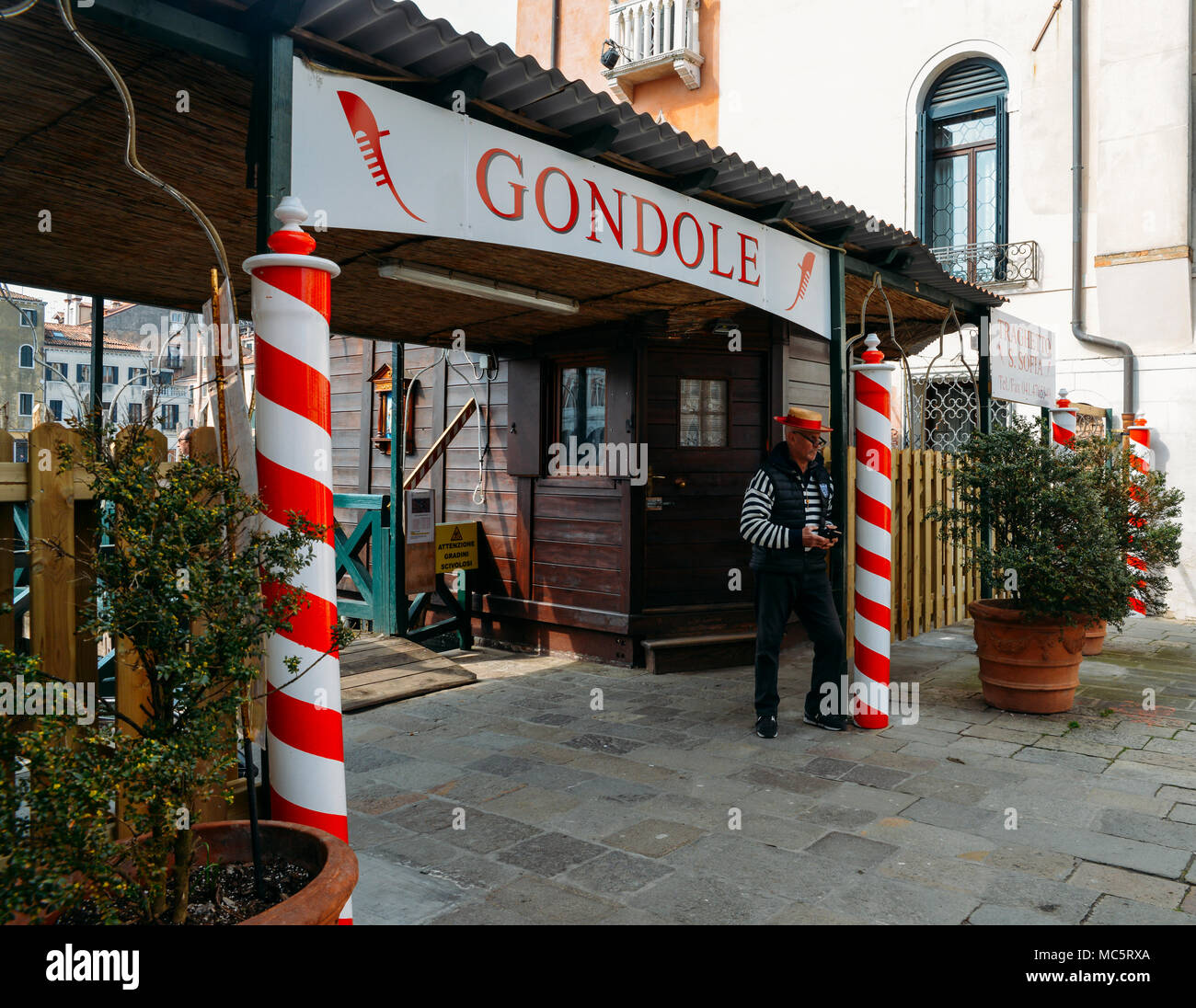 Venise, Italie - Mars 28th, 2018 : Gondolier détend à côté d'un signe de la publicité des services d'équitation gondole Banque D'Images