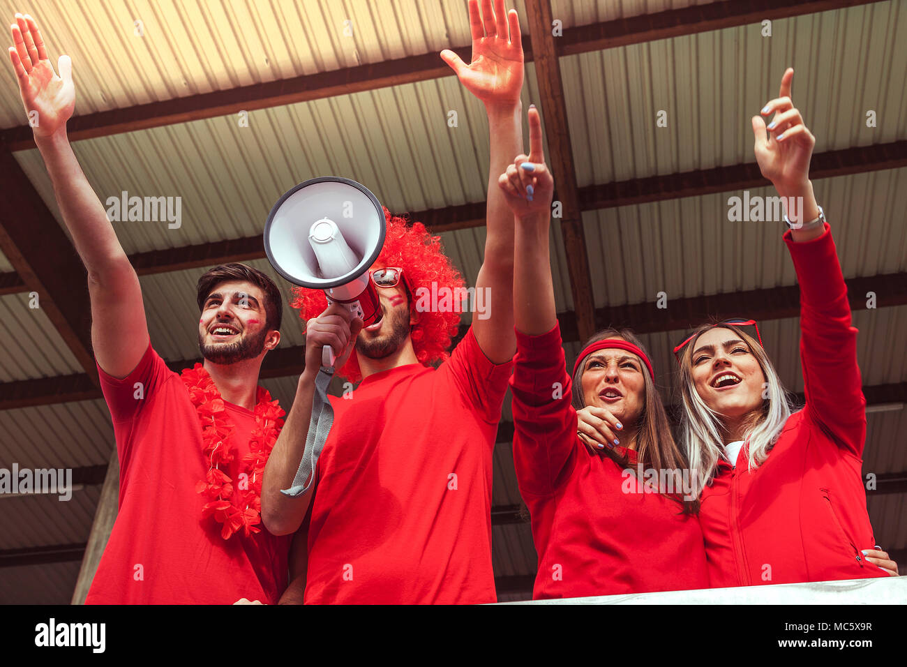 Groupe de fans vêtus de couleur rouge en regardant un événement sportif