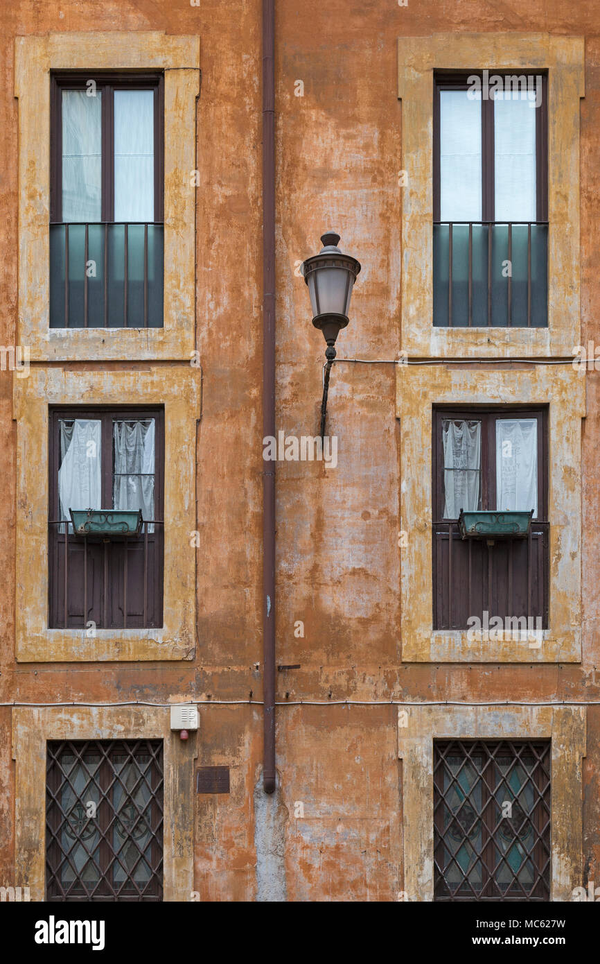Une façade pour un bloc d'appartement à Rome, en Italie, dans des tons de terre typique avec un réverbère sur le mur et windows avec quelques boîtes, mais pas de plan Banque D'Images