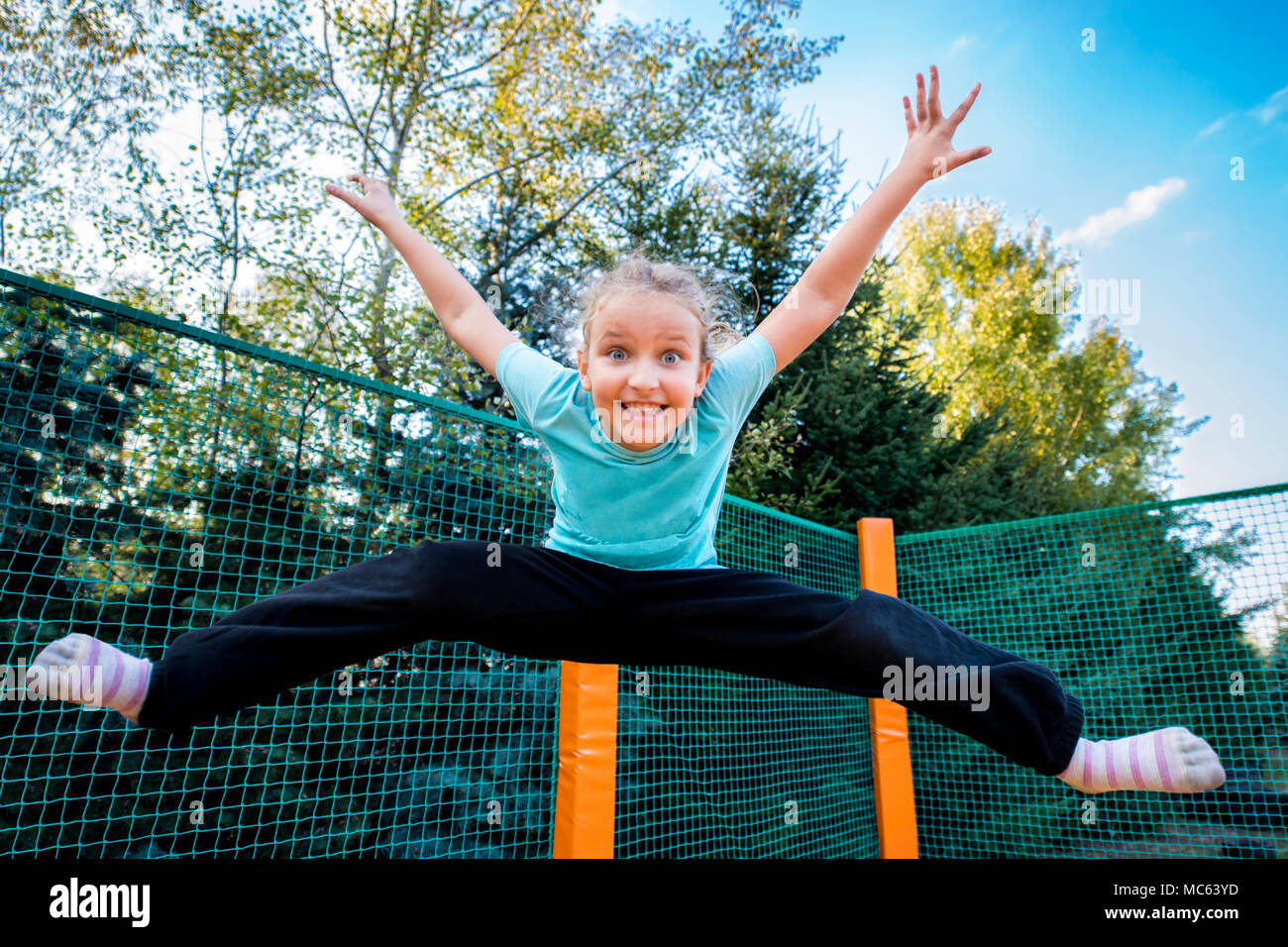 Happy woman jumping haut sur un trampoline sur une journée ensoleillée à l'extérieur. Banque D'Images