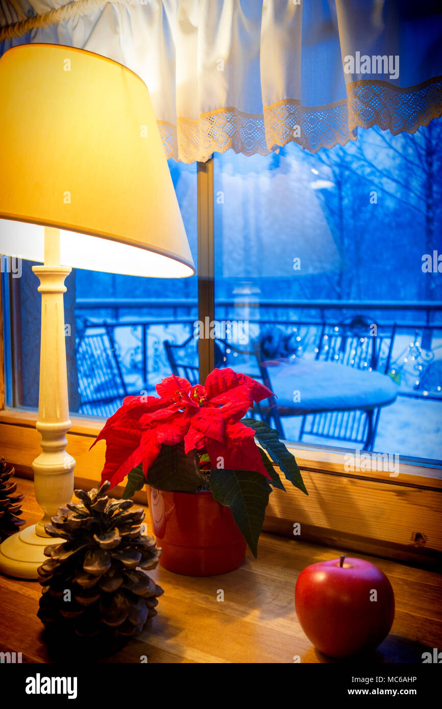 Lampe chaleureuse et décorations de Noël sur un rebord de fenêtre, avec paysage d'hiver vu à travers la fenêtre. Banque D'Images