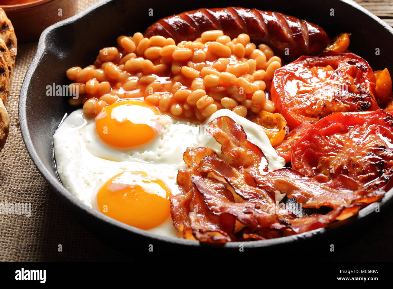 Petit déjeuner anglais avec des saucisses, des tomates grillées, des œufs, du bacon et des haricots sur le poêle. Banque D'Images