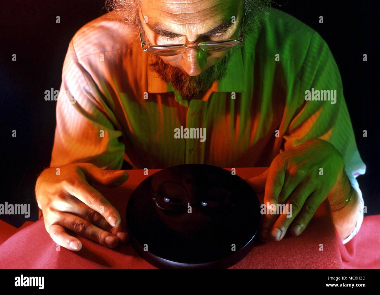 SCRYING - Un homme regardant dans une scrying glass, ou d'un spéculum, surface noir poli. La surface est utilisée comme une image de décisions autoscope, pour la projection d'images de l'esprit Banque D'Images