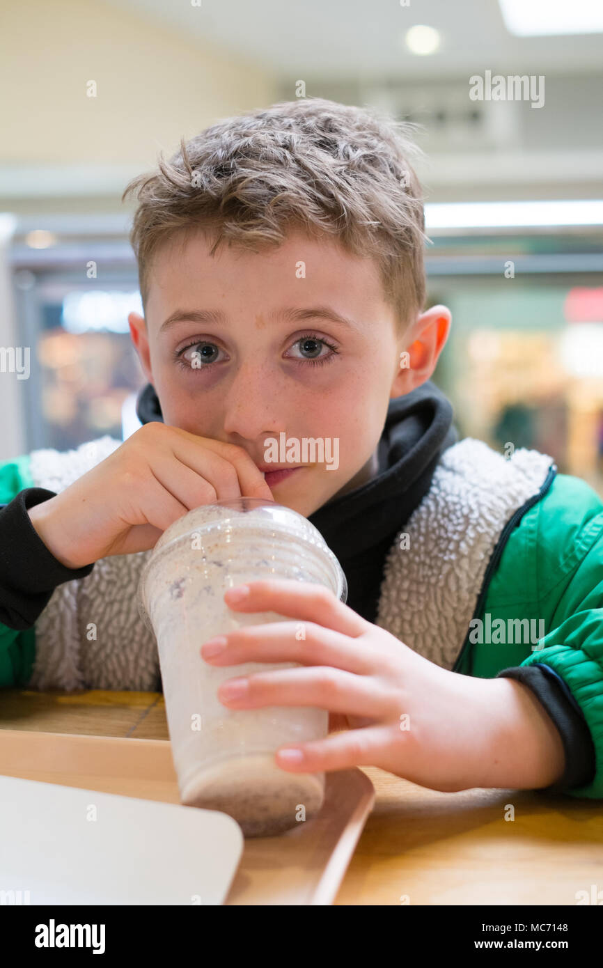 Garçon de huit ans avec un grand biscuit chocolat lait frappé, Londres, l'aéroport de Gatwick, Angleterre, Royaume-Uni. Banque D'Images