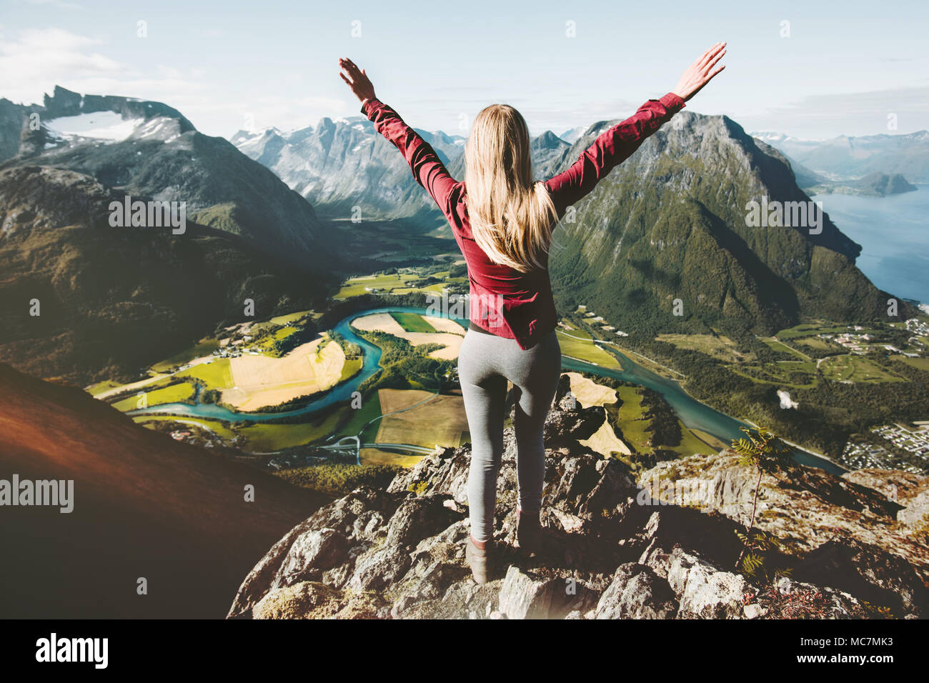 Happy traveler femme les bras levés debout sur la falaise au-dessus de la vallée de montagnes voyage paysage de vie sain vacances d'aventure en Norvège Banque D'Images
