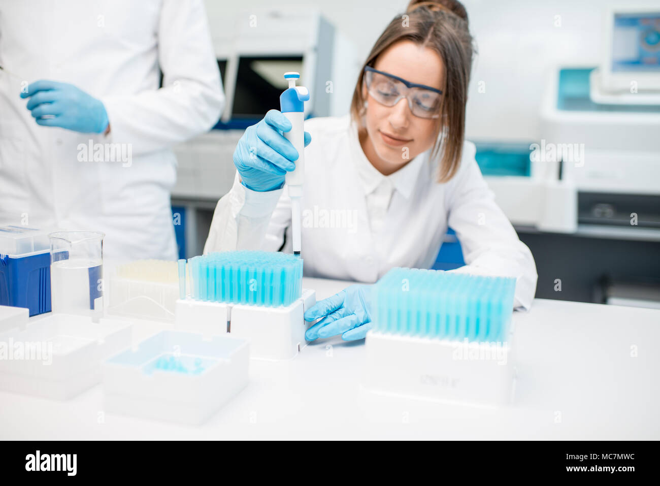 Jeune femme Auxiliaire de laboratoire en uniforme et lunettes de protection travaillant avec des tubes à essai dans le laboratoire médical Banque D'Images