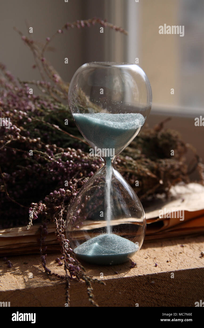 Le temps passant, sandglasses avec sable bleu, fleurs, bois Banque D'Images