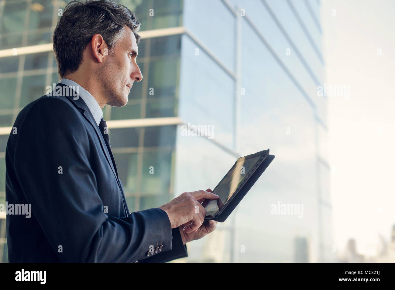 Man with digital tablet par fenêtre dans immeuble Banque D'Images