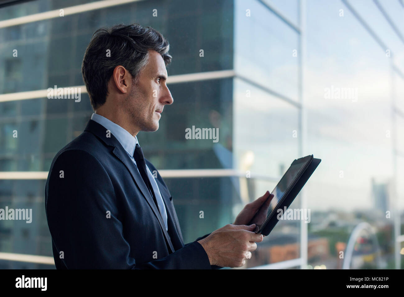 Man with digital tablet par fenêtre dans immeuble Banque D'Images