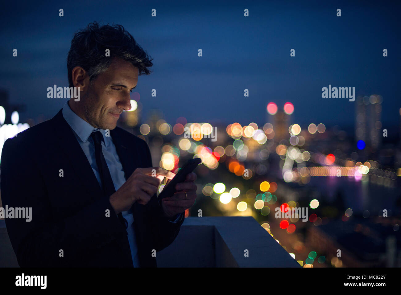 Homme d'affaires sur des tours à l'aide de téléphone mobile sur le toit Banque D'Images