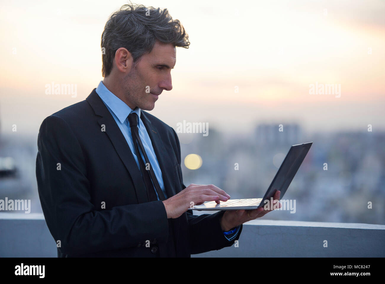 Businessman using laptop on rooftop Banque D'Images