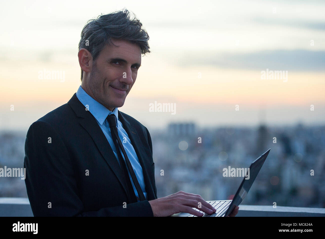 Businessman using laptop on rooftop Banque D'Images