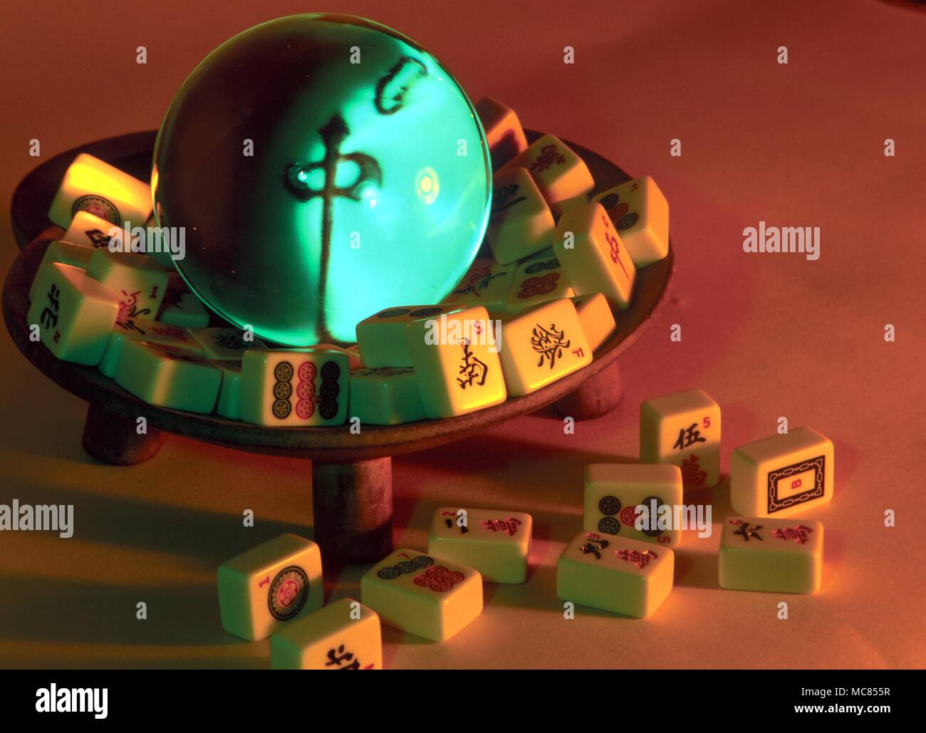 Jeu de dés et de Mah Jong Chinois pièces, autour d'une boule de cristal, à travers lequel un caractère chinois ('milieu') peut être vu. Banque D'Images