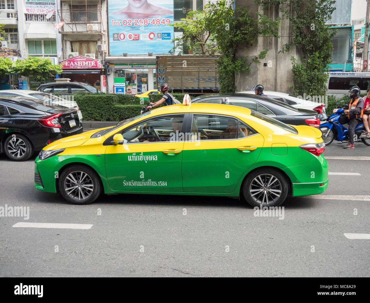 Un taxi jaune et vert sur une route à Bangkok en Thaïlande Banque D'Images