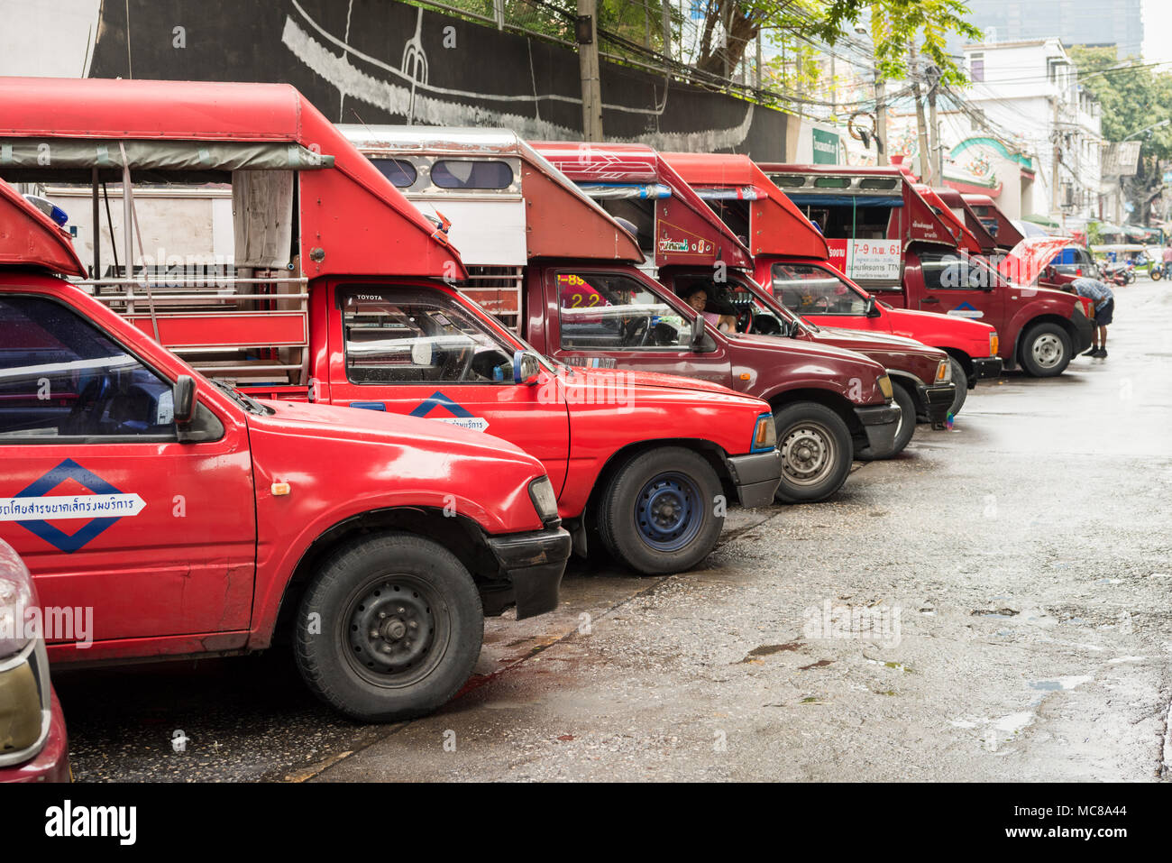 Une rangée de camions rouge ou cars alignés à l'extérieur du marché aux fleurs de Bangkok prêt à transporter des marchandises Banque D'Images