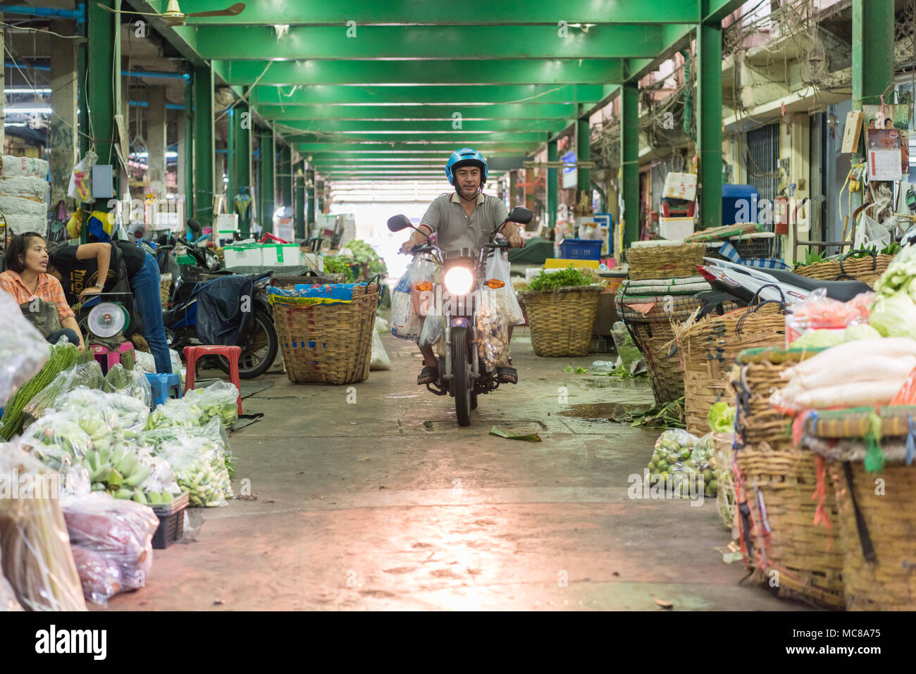 Un homme conduit une moto dans un couloir à travers le marché aux fleurs à Bangkok en Thaïlande Banque D'Images