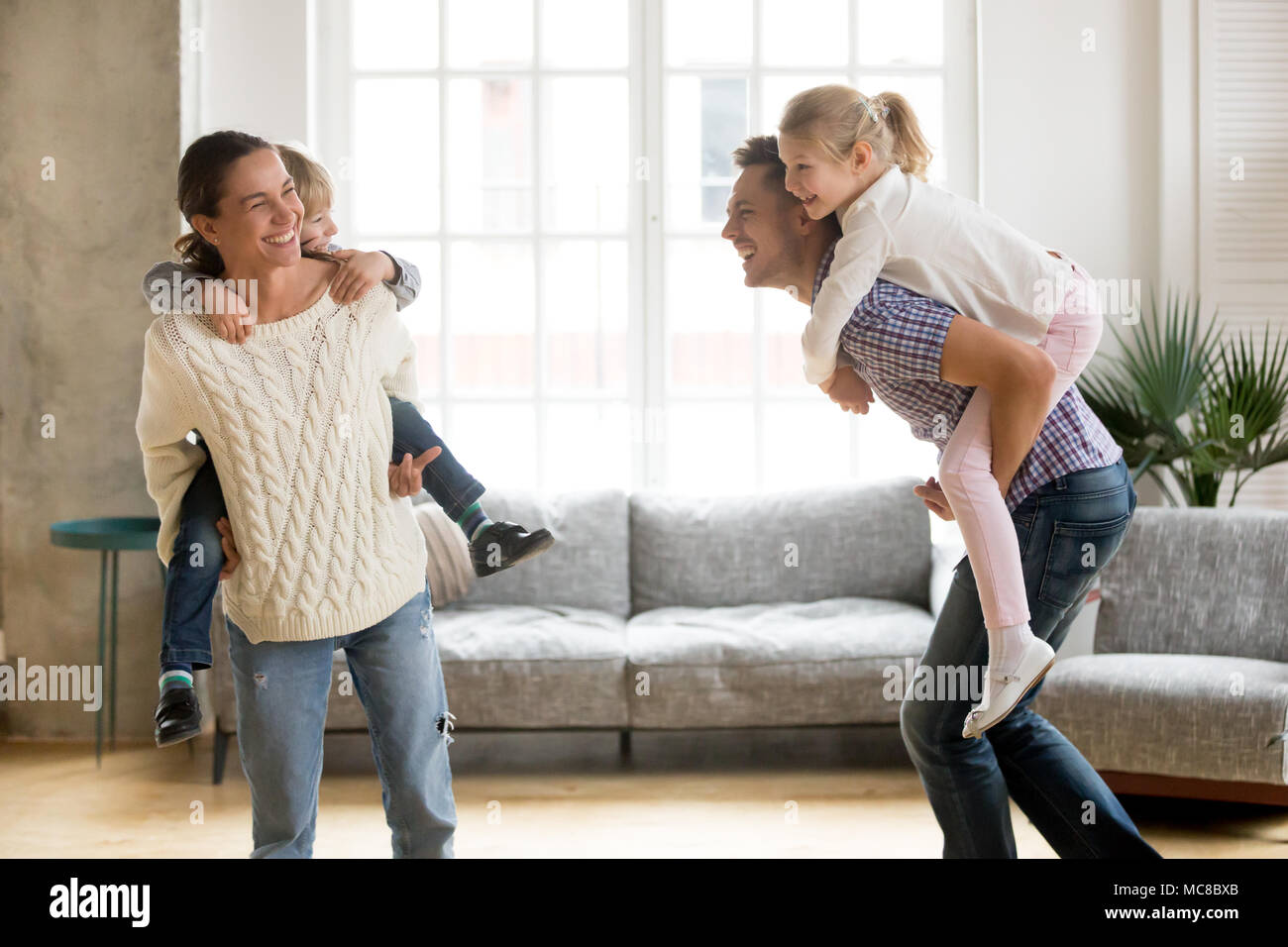 Les parents sur les enfants rire holding back donnant aux enfants piggyback ride jouer ensemble à la maison, en famille joyeux jeu drôle actifs ensemble, tr Banque D'Images