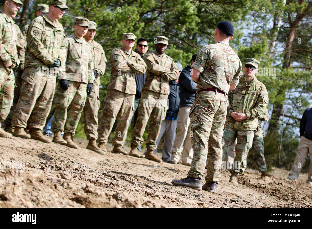 Le personnel de l'armée britannique Le Sgt. Joe Ferries, ingénieur de combat avec le 22e Régiment du génie, 8e Brigade du génie, demande à un groupe de soldats américains, marines, et du Département de la défense des civils sur la façon de contrôler à distance un Terrier armored digger lors d'un équipement mixte multinationale de l'entraînement à Grafenwoehr Domaine de formation, l'Allemagne, le 2 avril 2018, en préparation d'une infraction complexe robotique de démonstration de concept. L'infraction complexe robotique Concept comprend l'emploi de la Robotique et Systèmes Autonomes (RAS) dans l'intelligence, de suppression, d'obscurcissement, et de réduction. Banque D'Images