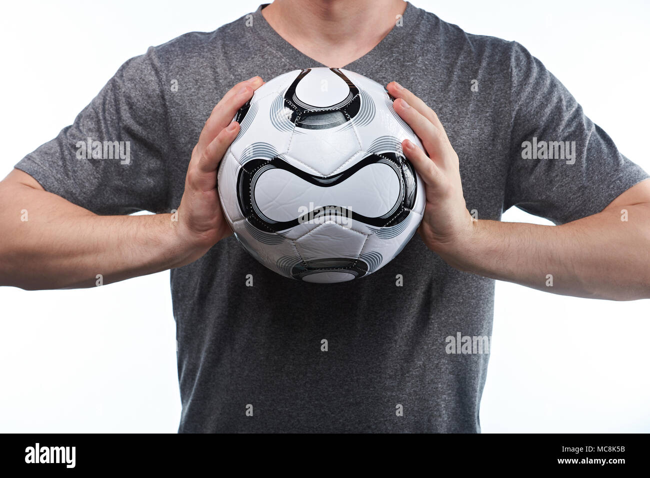 Football homme attraper ballon à deux mains sur fond gris Banque D'Images