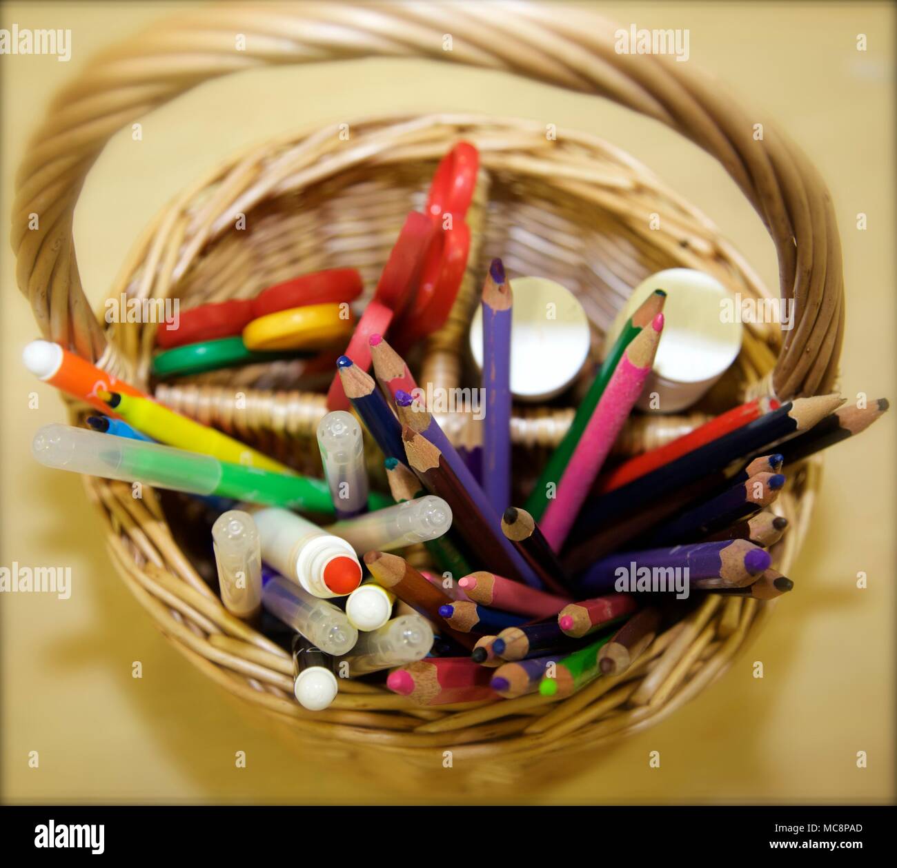 Crayons, stylos, colle et ciseaux dans un panier en osier Banque D'Images