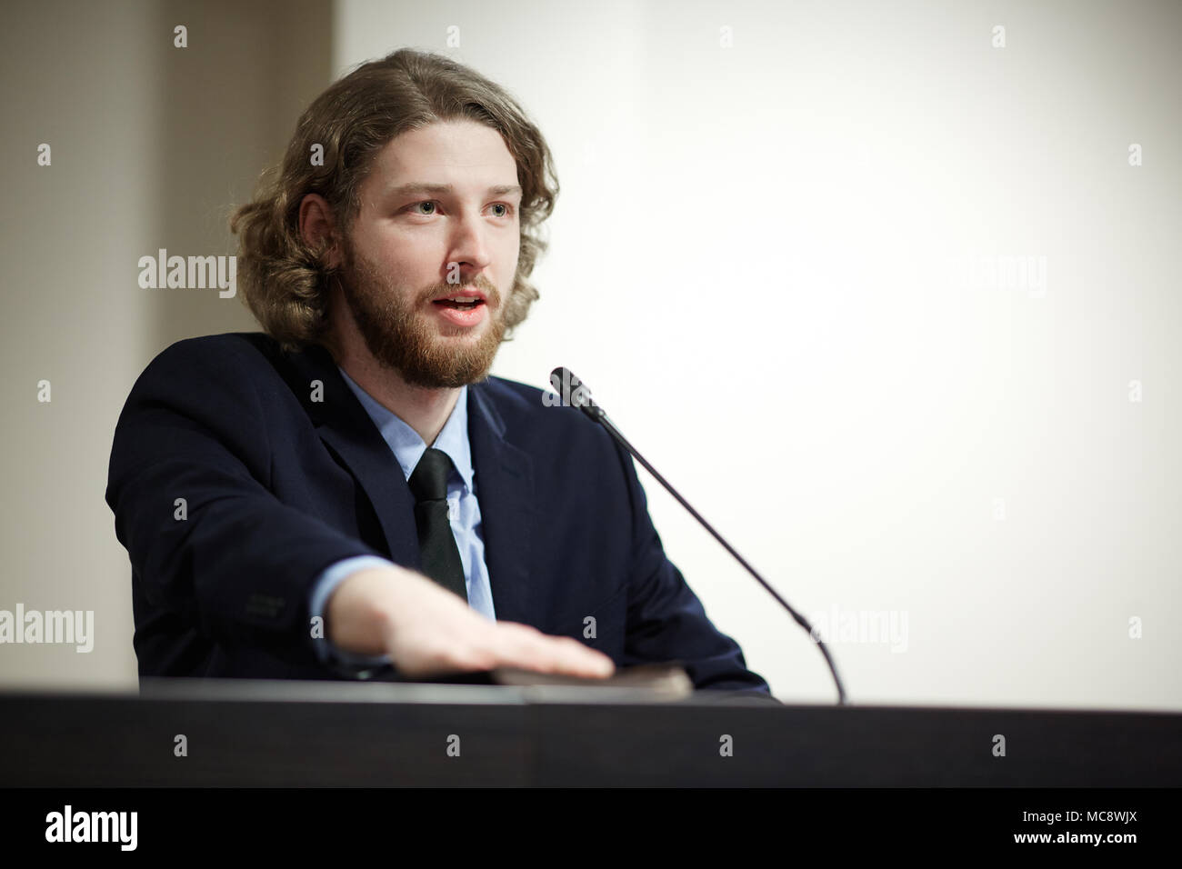 Les jeunes délégué confiant parlant en micro d'humains au cours du sommet politique ou d'une conférence Banque D'Images
