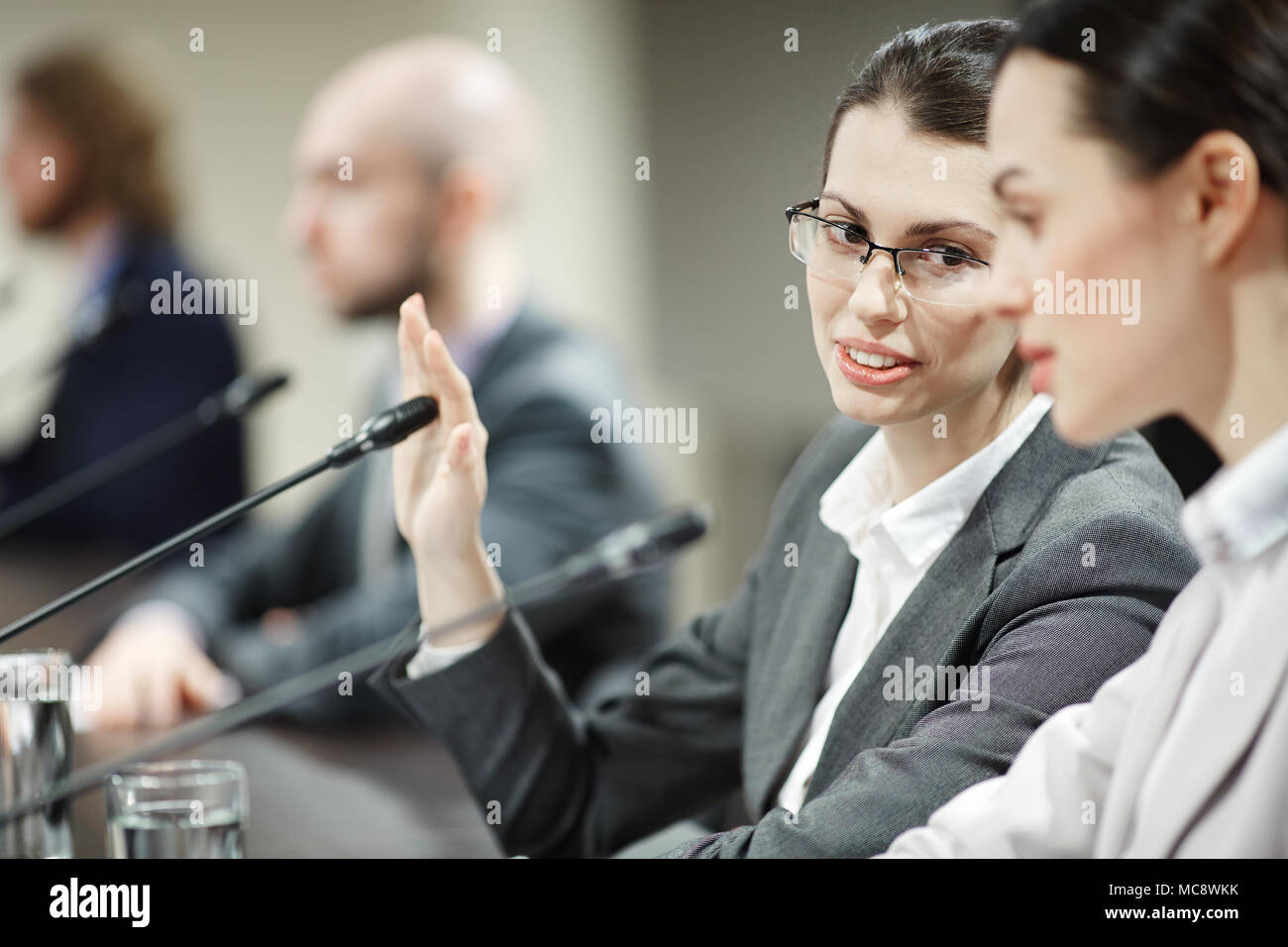 L'une des femmes d'affaires couvrant mike à la main lors de la consultation de son collègue ou son délégué Banque D'Images