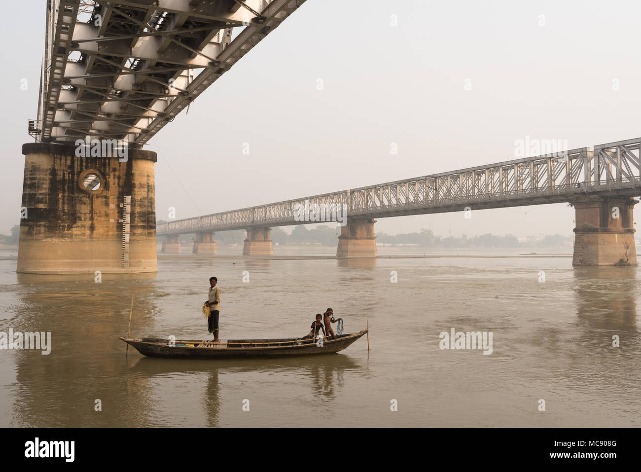 Un homme et ses enfants sur un bateau de pêche à proximité des ponts sur le fleuve Gandak, Sonepur, Inde. Banque D'Images