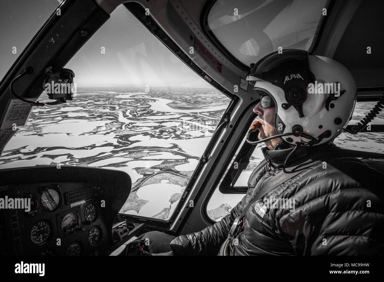 Pilote d'hélicoptère mâle dans ses 40 ans, volant dans le delta de Beaufort pendant l'hiver, dans les Territoires du Nord-Ouest, dans l'Arctique canadien. Banque D'Images