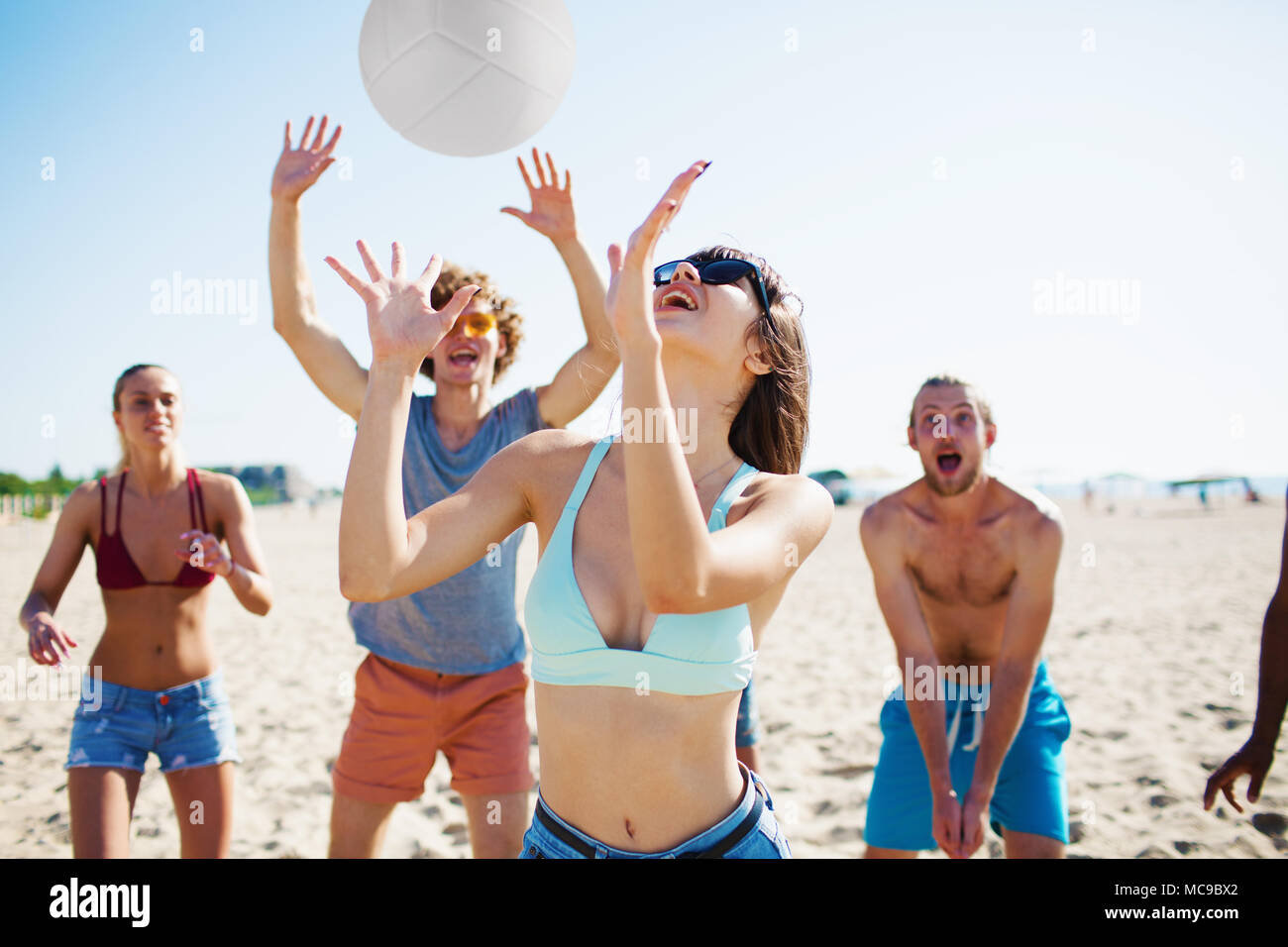 Groupe d'amis jouant au beach-volley sur la plage Banque D'Images