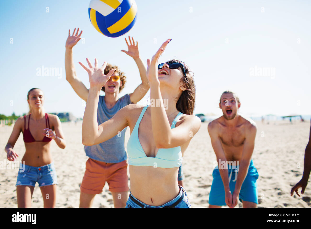 Groupe d'amis jouant au beach-volley sur la plage Banque D'Images