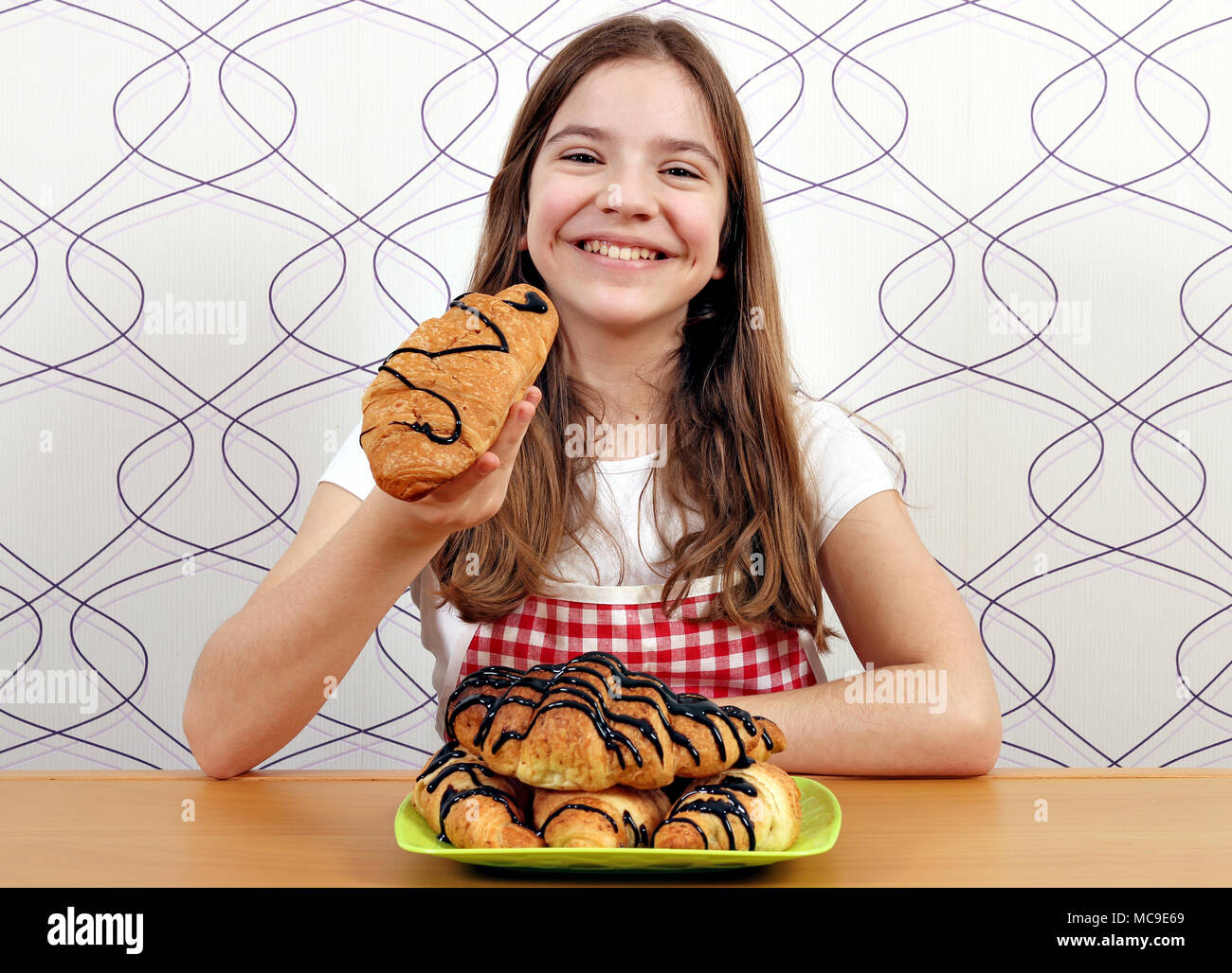 Happy little girl mange un croissant avec du chocolat Banque D'Images