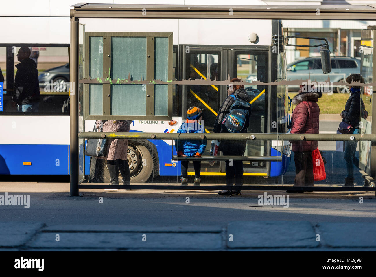 Riga, Lettonie, 11 avril 2018 : Les personnes en attente de l'autobus à l'arrêt de bus. Vue depuis l'arrière. Banque D'Images