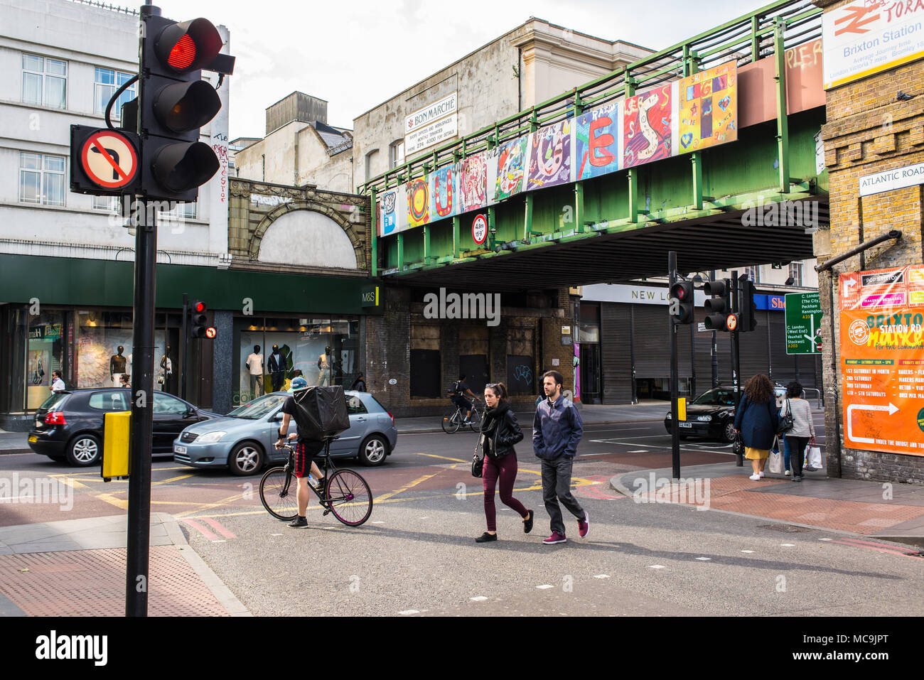 Les personnes qui traversent la route, à la jonction entre la route de l'Atlantique et Brixton Road avec vue sur le pont de Brixton avec peinture murale représentant l'installation art Banque D'Images