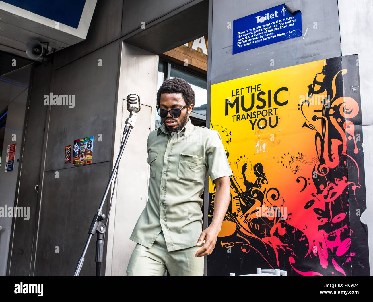 Musicien chanteur musicien ambulant Afro l'exécution devant une affiche disant Laissez la musique vous transporter à l'entrée de la station de métro de Brixton dans le Sud Banque D'Images