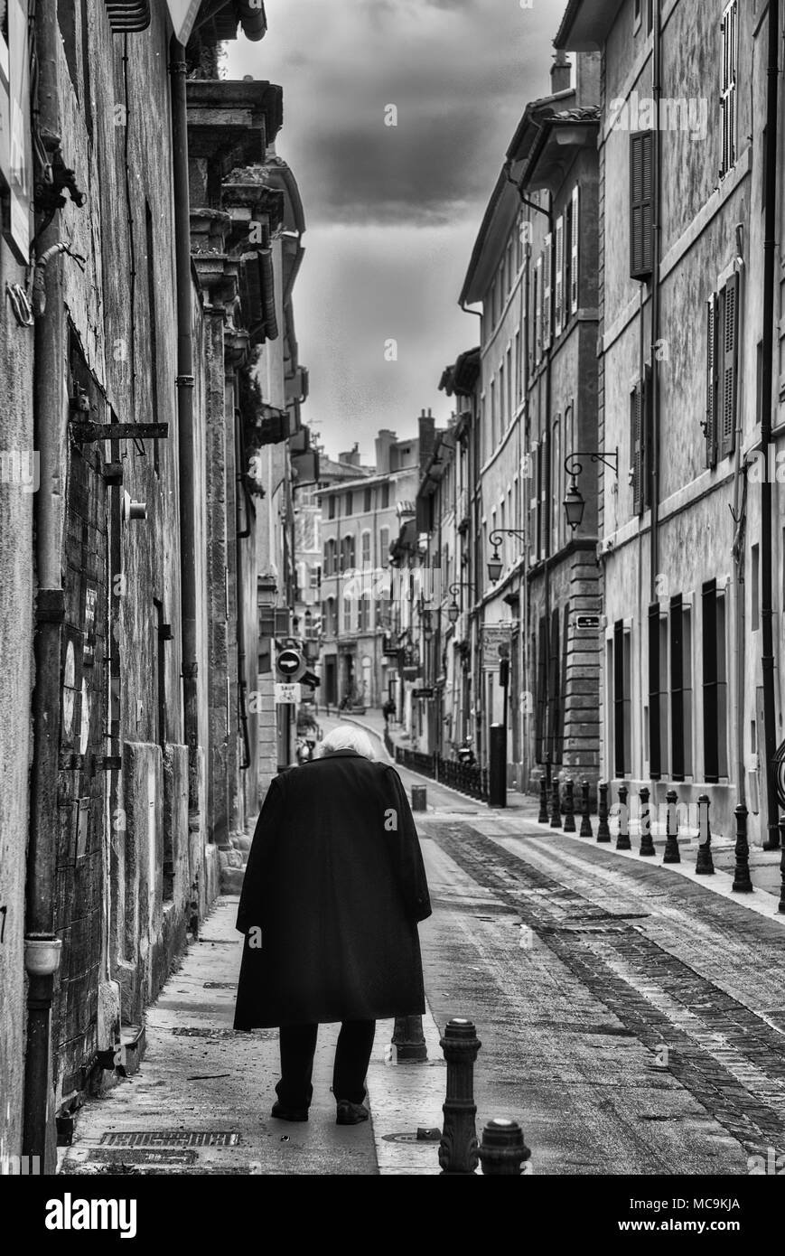 Noir et blanc photo verticale de dirigeant d'une personne sur une petite rue française, ni les bâtiments, ni la personne sont reconnaissables Banque D'Images