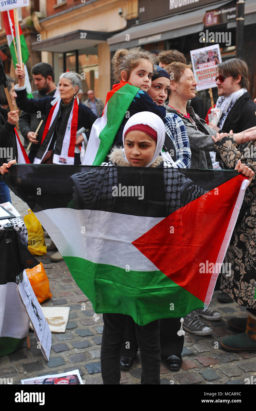 Londres, Royaume-Uni 14 avril 2018 jeune fille musulmane tenant un drapeau palestinien lors d'une démonstration en face de l'homme palestinien l'ambassade israélienne à Kensington, Londres, Royaume-Uni. La manifestation était légèrement rauque assez bien pris en charge avec environ 60 personnes présentes. Il a été appelé à protester contre la persistance de la tension dans la bande de Gaza, à la suite des récentes violences entre les deux parties. Londres, Royaume-Uni 14 avril 2018 rassemblement de cinq manifestants pro-Israël chahute la démonstration de l'autre côté de la route. Crédit : Michael Preston/Alamy Live News Banque D'Images