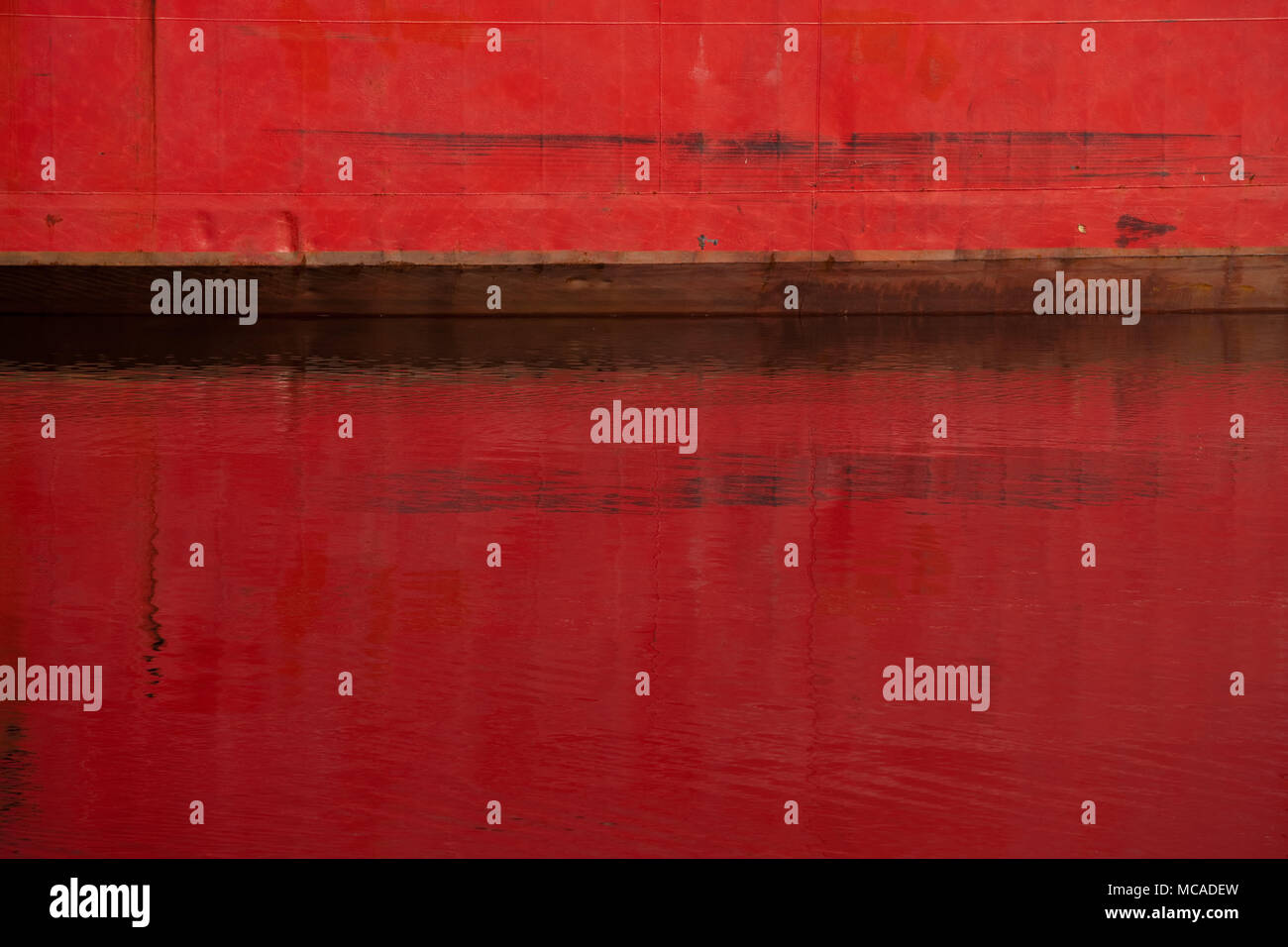 Un gros plan d'une partie d'un bateau rouge reflétée sur la surface d'une rivière Banque D'Images