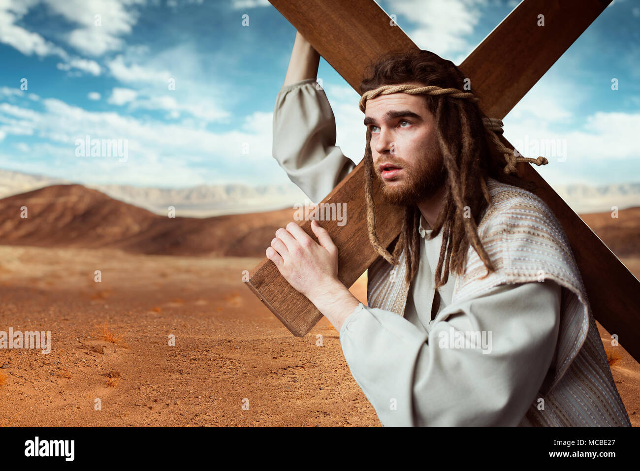 Jésus Christ avec croix en désert, ciel nuageux Banque D'Images