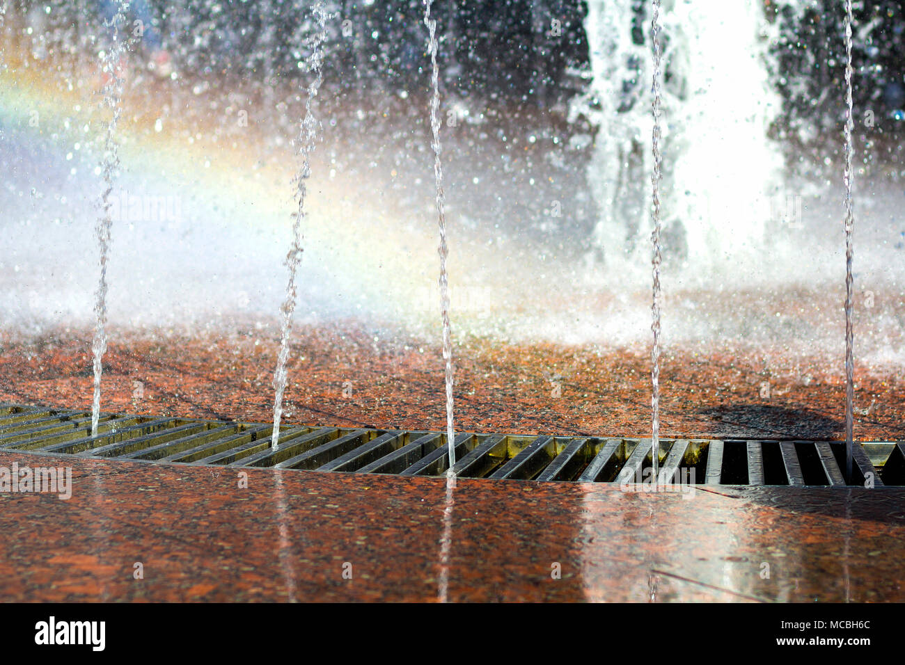 Close up de belle ville fontaine. La hausse des projections de flux mince cristal clair transparent, brillant de l'eau fraîche des gouttes. Rainb floue multicolores Banque D'Images