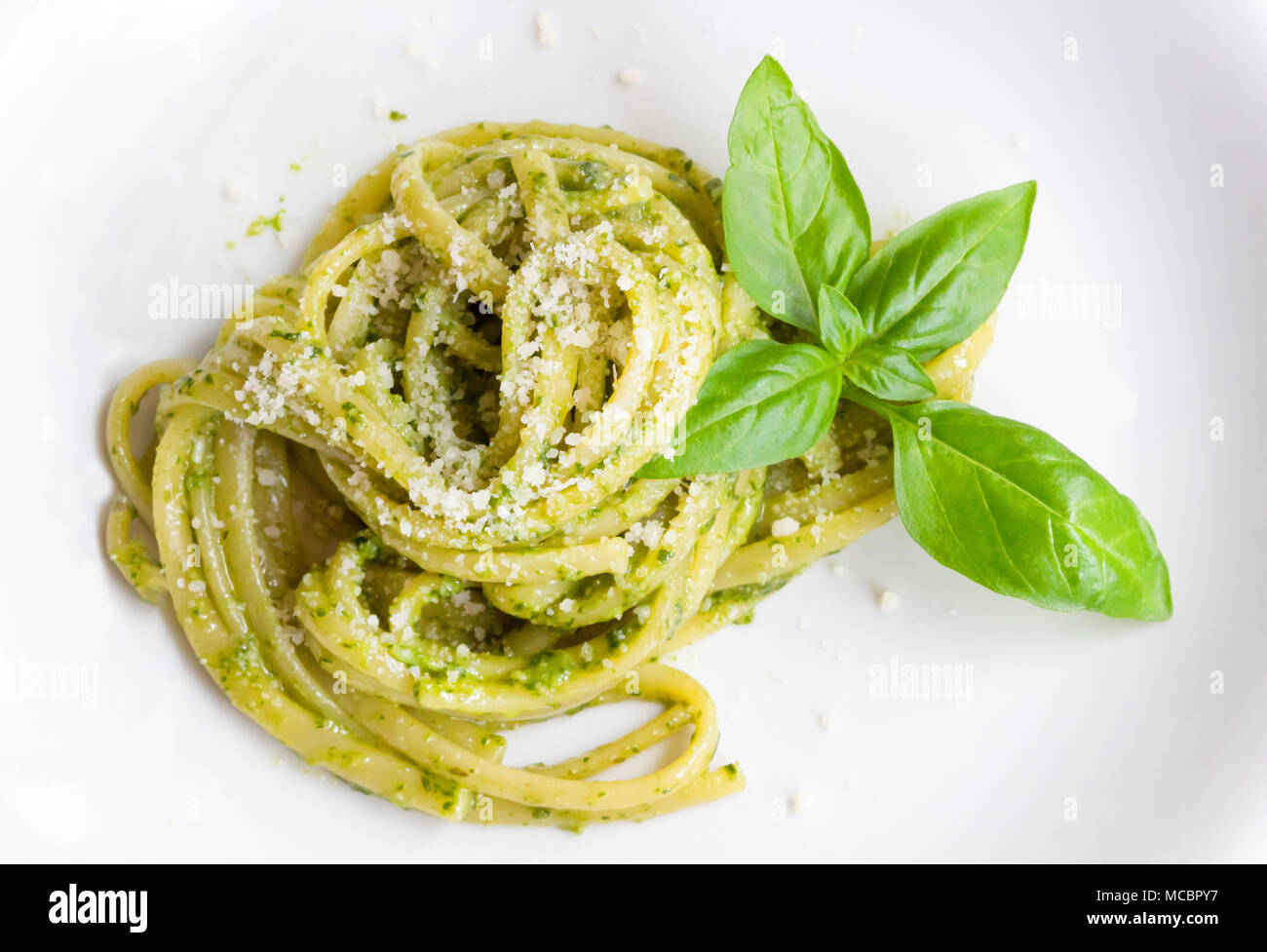 Les pâtes spaghetti avec sauce verte pesto original à Gênes (Genova) Italie sur plaque blanche fond, pâtes avec pesto de basilic herbes arrière-plan. Banque D'Images