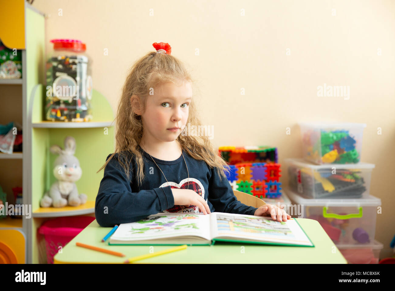 Cute little girl faire leurs devoirs, lire un livre, des pages à colorier, écrire et peindre. Les enfants d'âge préscolaire apprennent à lire et écrire. Tout-petits créatifs. Teachin Banque D'Images