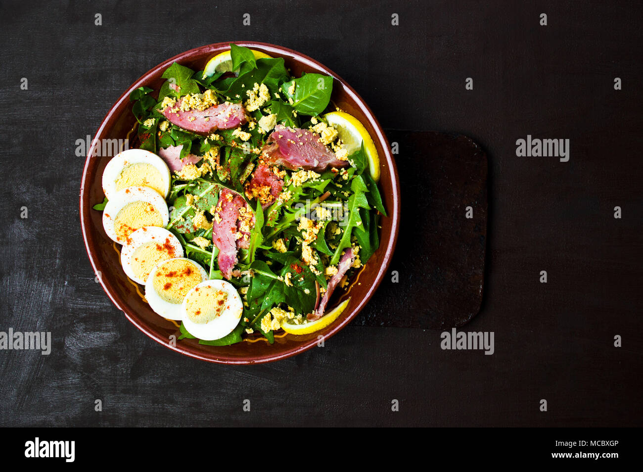 Salade de pissenlit avec la viande et les œufs dans un bol de citron vue supérieure Banque D'Images