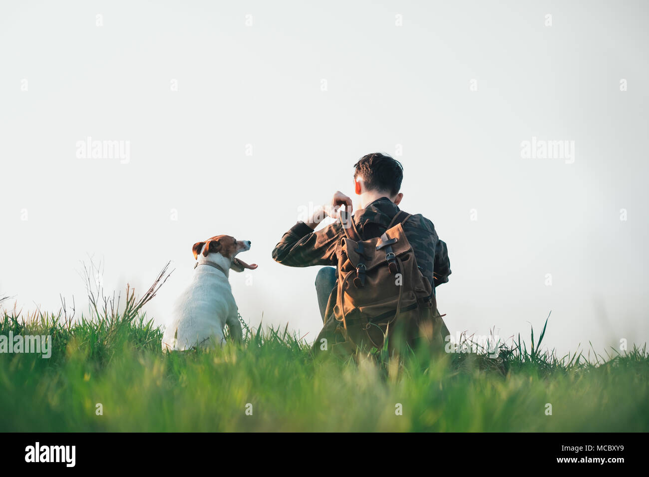 Adolescent sur pelouse verte avec petit chien blanc Banque D'Images