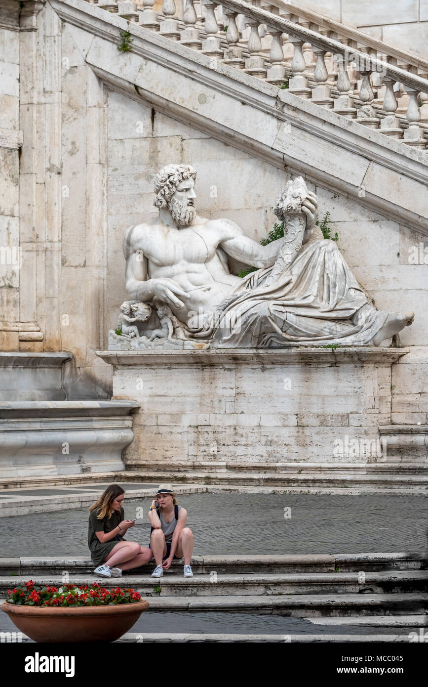 Deux jeunes femmes touristes reste avant Palazzo Senatorio et sculpture de Tiber à Piazza del Campidoglio en dehors du Musée Capitolin, Rome, Italie Banque D'Images